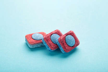 Red and blue tablets for dishwashing machine. Detergents for home hygiene. Dishwasher capsules on blue background. top viewの写真素材