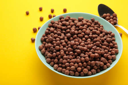 Chocolate corn balls in blue bowl on yellow background. top view.の写真素材