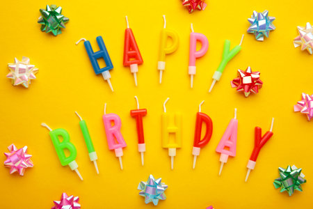 Text Happy Birthday with birthday assocories, candles and confetti on yellow background. top view.の写真素材