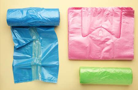 A lot of colored plastic bags rolls on a yellow background. top view.