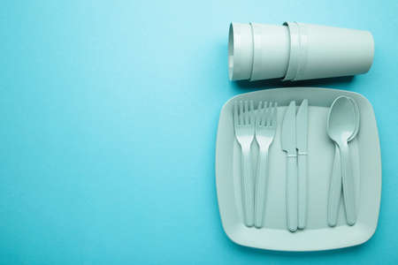 Bright plastic disposable tableware on blue background. top viewの写真素材