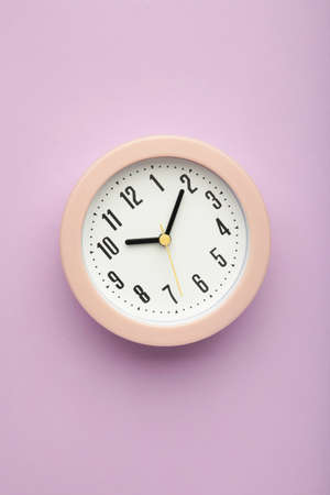 Pink clock on purple background. vertical photo