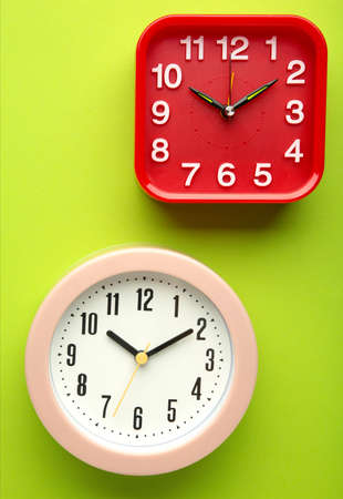 Pink and red wall clock on green background. top view