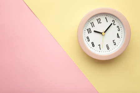 Pink clock on beige and pink background. top view. Space for text