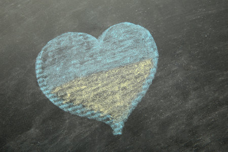 Heart shape chalk drawing on blackboard in Ukrainian Flag colors: blue and yellow. top viewの写真素材