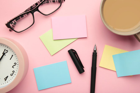 Photo above of sticky notes, cup of coffee and glasses on the pink background. top view