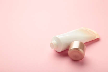 Top view blank label facial skincare tube bottle with lid open on pink background. Space for textの写真素材
