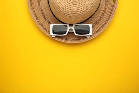 Straw hat and sunglasses on yellow background. Summer holiday, vacation, travel concept. Flat lay, top view, copy space. Minimal styleの写真素材