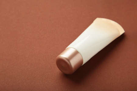 Tube of cream or gel white plastic product on brown background. top view. Space for text