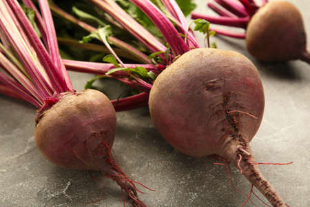 Red Beetroot with green leaves on gray background. top view.