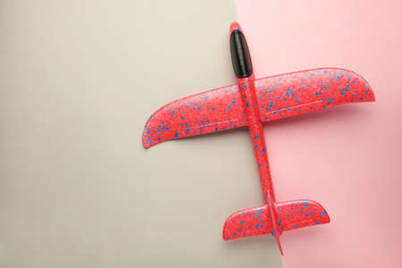 Flat lay of miniature red toy airplane on pink and gray background. top view.