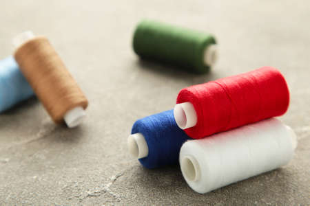Color sewing threads on gray background, top view