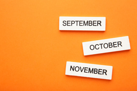 Wooden cubic of september, october, november on orange background. Autumn month. top viewの写真素材