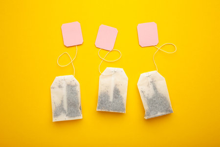 Tea bags with pink labels on yellow background. Minimalism, flat lay, place for text. top viewの写真素材