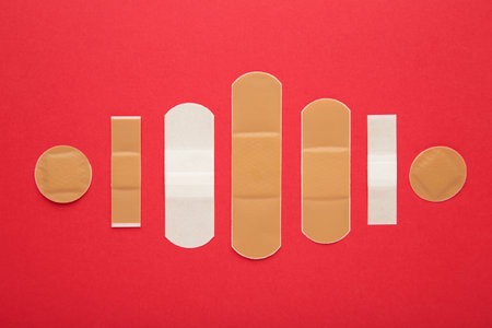Adhesive bandage sticking plaster on red background. Space for text. top viewの写真素材