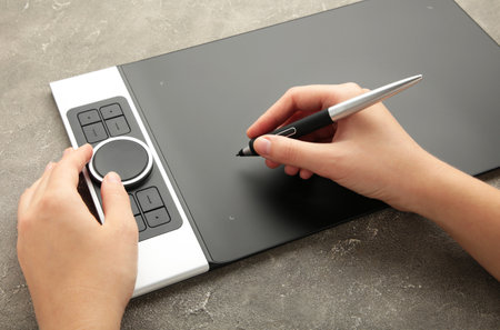 Graphic designer using digital tablet on gray background. top view
