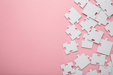 Uncompleted elements of a white puzzle on pink background. Space for text. top viewの写真素材