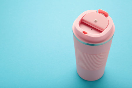 Pink thermo cup or thermos mug for tea or coffee on blue background. Hot beverage. Top viewの写真素材