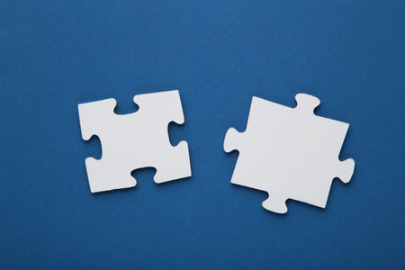 Two blank white puzzle pieces on blue background. top viewの写真素材