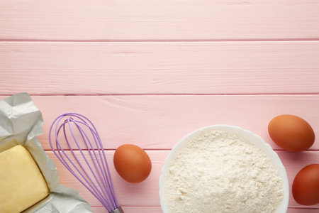 Ingredients for baking or cooking, egg flour, rolling pin butter, milk on a pink wooden background...