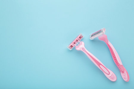 Pink razors for hair removal on blue background. top viewの写真素材