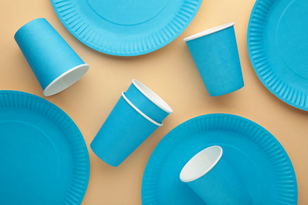 Eco-friendly disposable utensils made of craft paper on beige background. Blue plates and paper...
