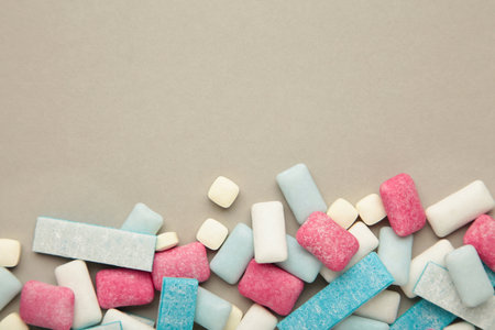 Different chewing gums on gray background. top view