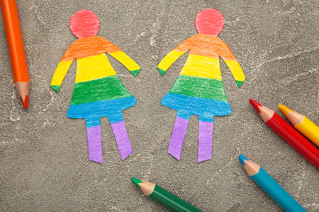 Paper women cut from paper and painted in LGBT colors with pencils. Concept of LGBT on gray background. Space for text. top view.の写真素材