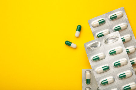 Medical blister packs with pills on yellow background. top view