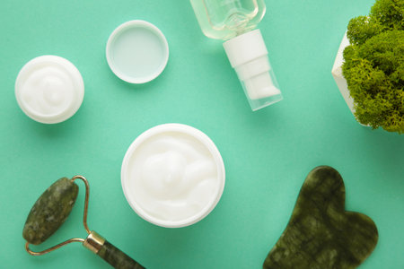 Face massage roller with cosmetic cream on mint background. top viewの写真素材