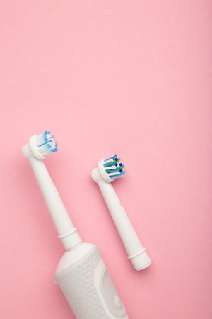 Modern electric toothbrush on pink background. Controlled tool for daily oral care. vertical photoの写真素材