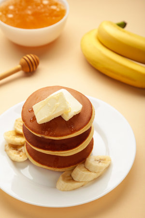 Plate with yummy banana pancakes on beige background. vertical photo. top viewの写真素材