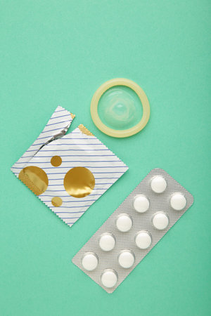 Contraceptive pills and condoms on mint background. concept of birth control. top view