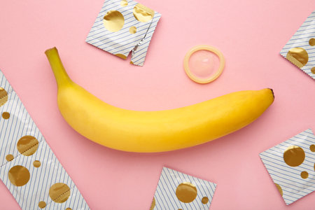 Condom and banana on pink background with copy space. top viewの写真素材