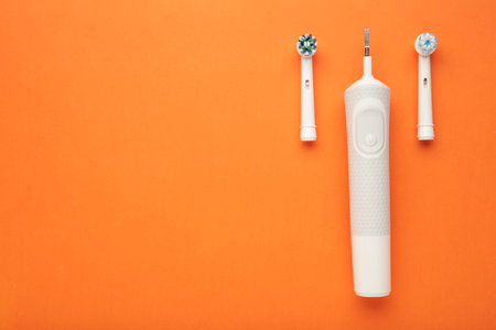 Modern electric toothbrush on orange background. Controlled tool for daily oral care. Space for textの写真素材