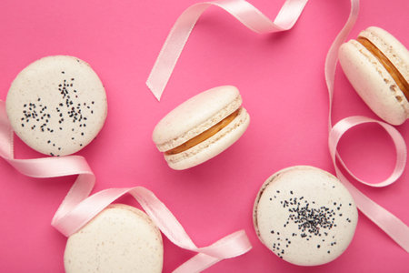 Light cake macaron or macaroon with ribbon on pink background. sweet background. Flat lay, top view, copy spaceの写真素材