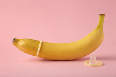 Condom and banana on pink background with copy space. top viewの写真素材