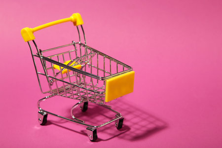 Mini shopping trolley on pink background. Space for textの写真素材