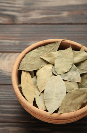 Bay leaves in wooden bawl on brown background. vertical photo. top viewの写真素材