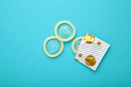 Opened condom in pack on blue background. A condom use to reduce the probability of pregnancy or sexually transmitted disease. top viewの写真素材
