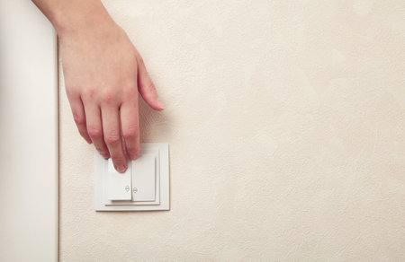 Female hand pressing light switch in apartment closeup. Space for text. top viewの写真素材