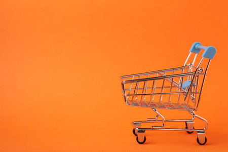 Mini shopping trolley on orange background. Space for textの写真素材
