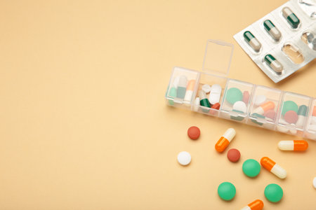 Daily pill box with medications and nutritional supplements on beige background. top viewの写真素材