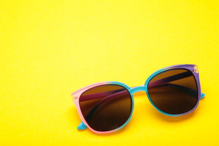 Colorful sunglasses on yellow background. Space for text