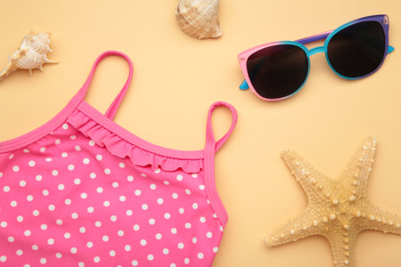 Summer kid's vacation concept - swimsuit with cute sunglasses on beige background. Holiday concept, fashion child. top viewの写真素材