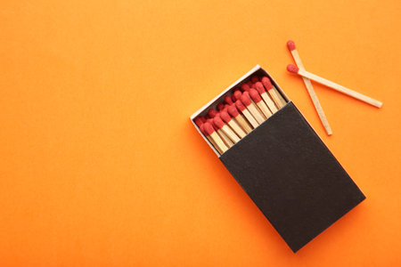 Box of matches with matches on orange background. Space for text. top viewの写真素材
