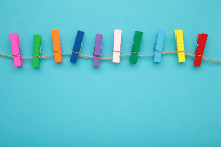 Colored wooden clothes pins on a rope on blue background. design elements. macro. top view