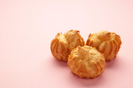 Homemade profiteroles with cream on pink background. Fresh baked golden profiterole. top view.の写真素材