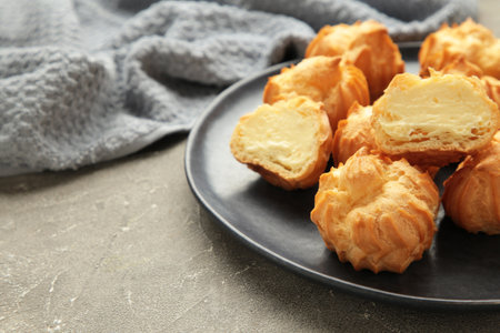 Homemade profiteroles with cream on plate on gray background. Fresh baked golden profiterole. Top view.の写真素材