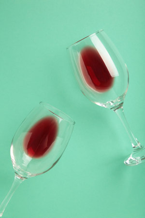 Glasses with red wine lying on mint background. Flat lay. Vertical photoの写真素材